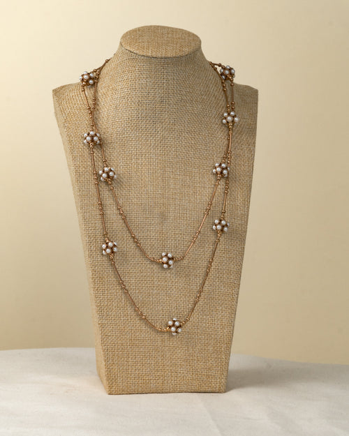 Collar largo de metal dorado con flores de perlas