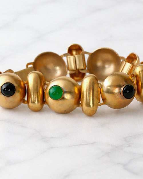 Brazalete de eslabones de metal dorado con cabujones de piedras verdes y negras